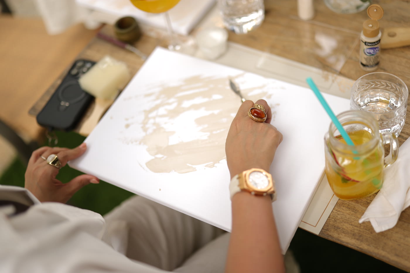 A hand at work on canvas — cream pigment, slow strokes